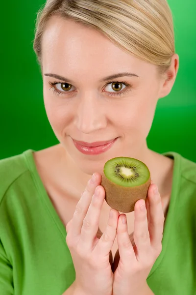 Healthy lifestyle - happy woman holding kiwi on green — Stock Photo, Image