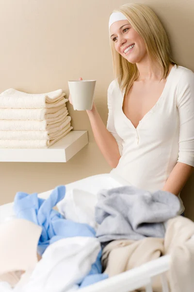 Stiratura di lavanderia - pausa di donna con bevanda Foto Stock