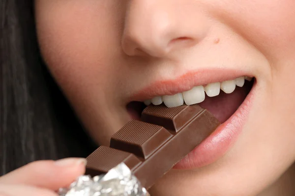 Chocolate - mujer de cerca muerde dulces —  Fotos de Stock