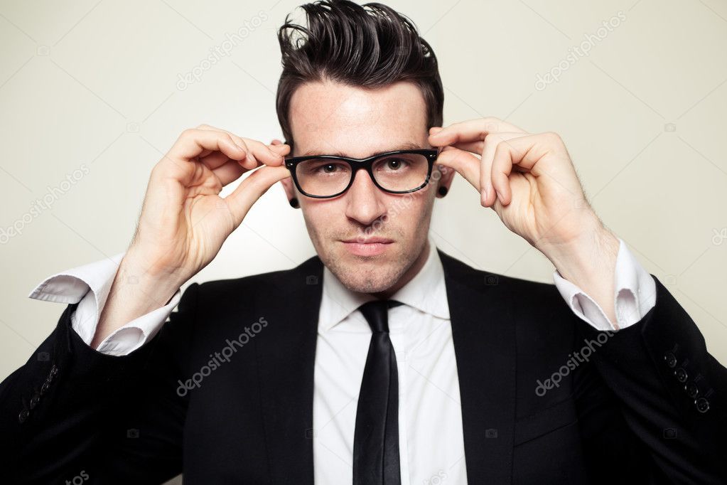 Confident young man holding black glasses.