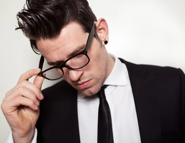 Jovem empresário segurando óculos pretos — Fotografia de Stock