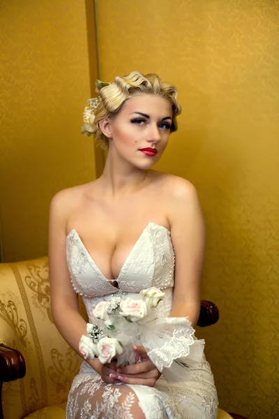 Невеста блондинка с букетом сидит на стуле — стоковое фото