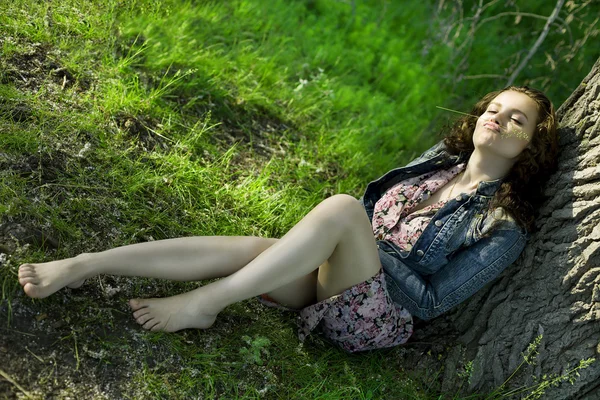 Una bella ragazza siede vicino a un albero — Foto Stock