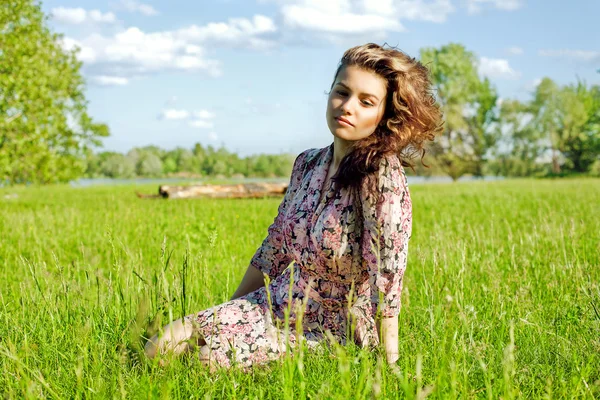 Розслаблена молода дівчина сидить на траві в парку - Відкритий — стокове фото