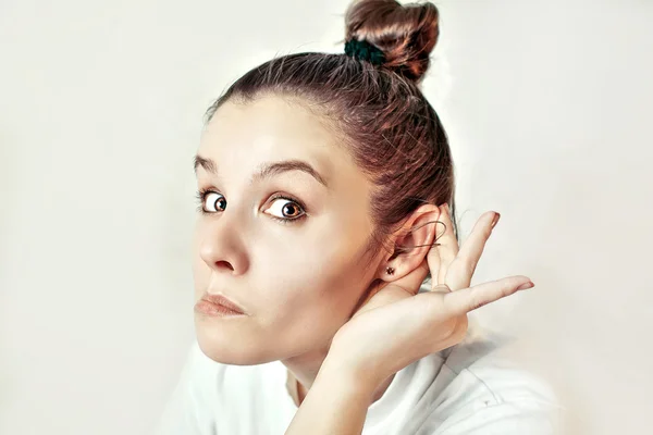 Meisje met haar hand op een oor te luisteren — Stockfoto