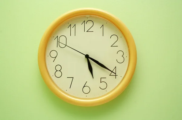 Yellow wall clock on the green — Stock Photo, Image