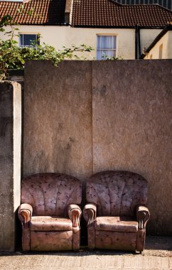 Armchairs on street or pavement in urban town area.trashed furniture, rubbish or litter by the road