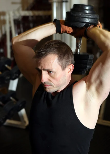 フリーウ エイトとトレーニング上腕三頭筋 建物の筋力の頭の上の男性の持ち上がるダンベル — ストック写真