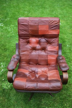 Retro leather designer armchair. danish 70's recliner furniture on grass lawn clipart