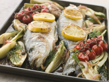 Pan of Whole Sea Bass Roasted with Fennel Lemon Garlic and Cherry Tomatoes on the Vine clipart