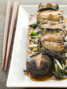 Plate of Fried Shitake Mushrooms with Shoyu Pac Choi and Bean sprouts and chopsticks clipart