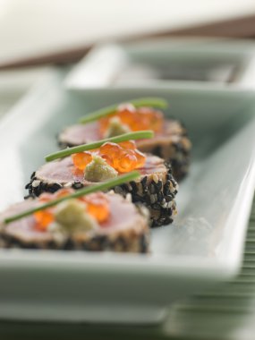 Plate of Seared Yellow Fin Tuna Rolled in Sesame seeds decorated with Wasabi and Salmon Roe clipart
