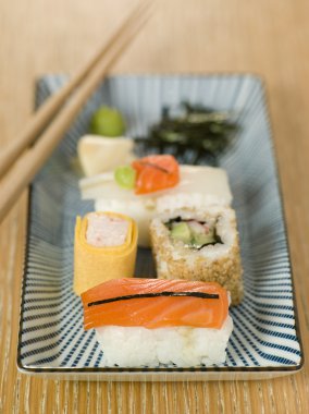 Plated Sushi with Wasabi Sushi Ginger and nori with chopsticks clipart
