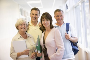 A group of adult students with backpacks standing in a campus co clipart