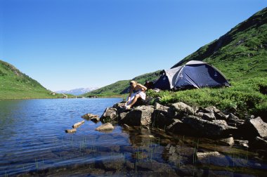 Young woman washing in lake next to camp clipart