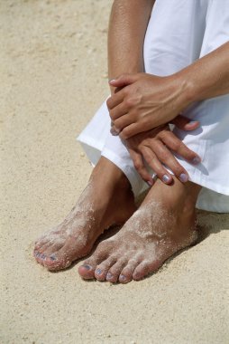 Young woman's feet covered in sand clipart