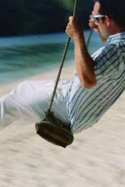 Man on swing at beach clipart