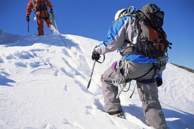 Young men mountain climbing on snowy peak clipart