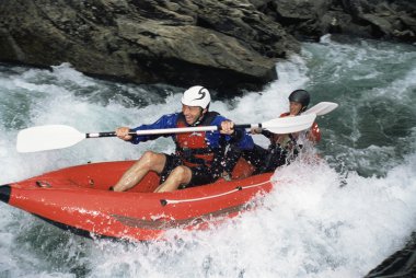 Two paddling inflatable boat down rapids clipart