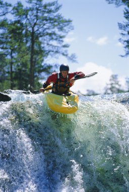 Young man kayaking on waterfall clipart