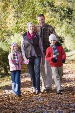 Grandparents and grandchildren on walk through autumn woods clipart