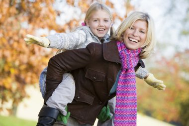 Mother giving daughter piggy back ride clipart