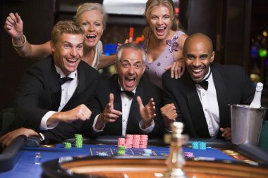 Group of friends celebrating at roulette table in casino clipart