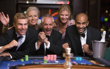 Group of friends celebrating win at roulette table in casino clipart