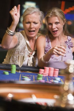 Two women gambling at roulette table clipart