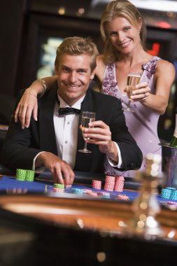 Couple gambling at roulette table in casino clipart