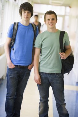 Male college students standing in university corridor clipart