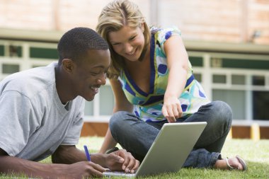 College students using laptop on campus lawn clipart