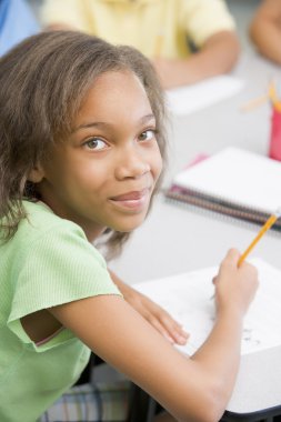 Elementary school pupil working at desk clipart