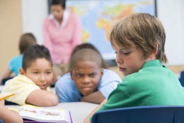 Boy being bullied in elementary school classroom clipart