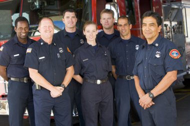 Portrait of firefighters standing by a fire engine clipart