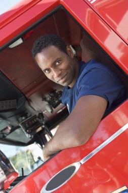 A firefighter sitting in the cab of a fire engine clipart