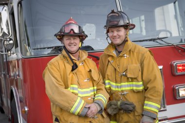 Portrait of two firefighters by a fire engine clipart