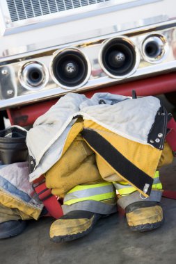 Empty firefighter's boots and uniform next to fire engine clipart