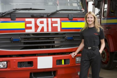 Portrait of a firefighter standing by a fire engine clipart