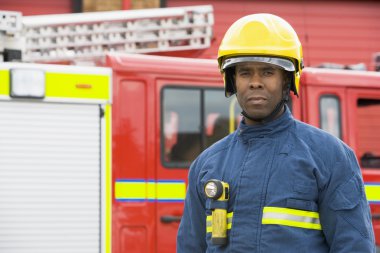 Portrait of a firefighter standing in front of a fire engine clipart