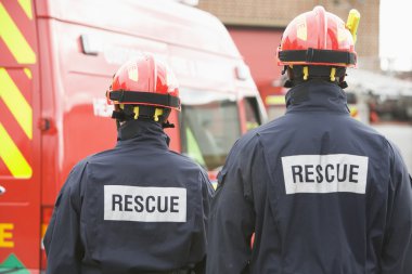 Firefighters standing by a small fire engine clipart