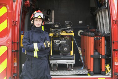 Firefighters standing by the equipment in a small fire engine clipart