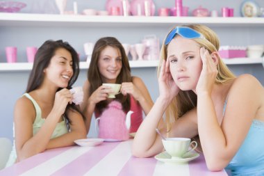 Two young women enjoying a tea party while one sits apart wearin clipart