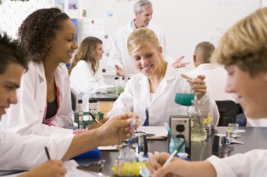 School children and their teacher in a high school science class clipart