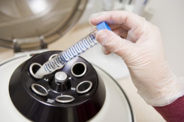 Embryologist putting sample into centrifuge clipart