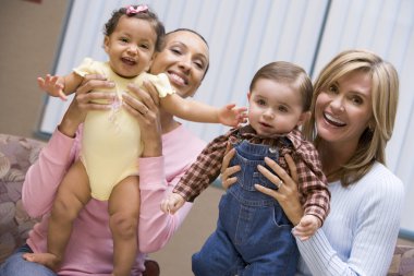 Two mothers holding young boy and girl clipart