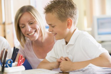 A schoolboy sitting with his teacher in class clipart