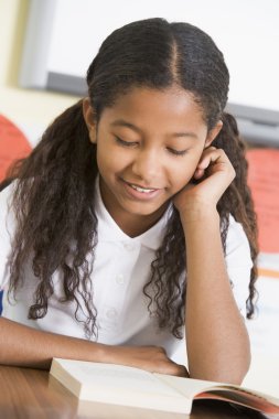 Schoolgirl reading a book in class clipart