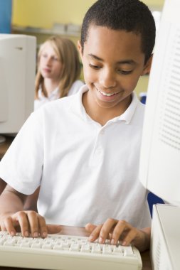 Schoolboy studying in front of a school computer clipart