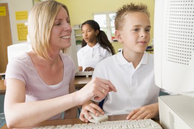 Teacher and schoolboy studying in front of a school computer clipart